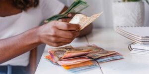 Sassa balance check — person counting South African Rand notes