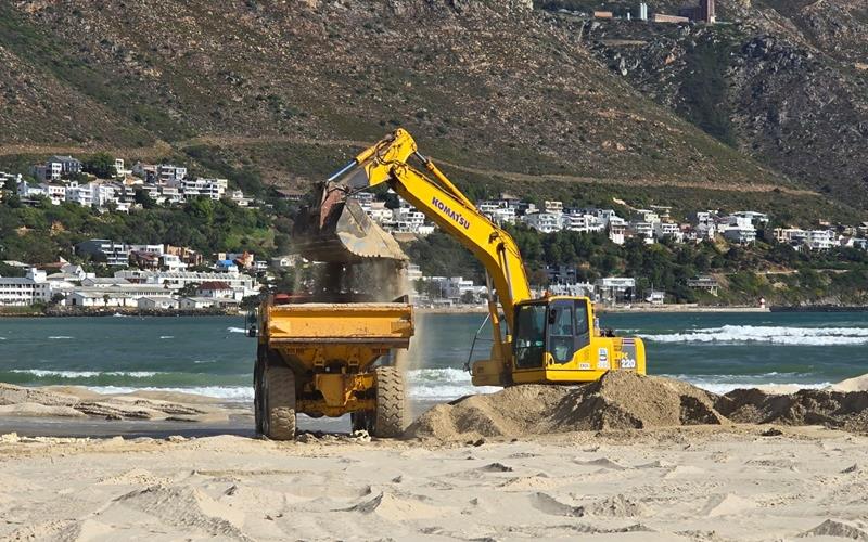 Graafmasjien laai sand op n trok by Fleur Park-strand naby Gordonsbaai tydens jaarlikse duine-onderhoud