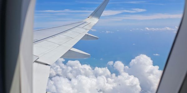 View of an aircraft wing from a passenger window above the clouds