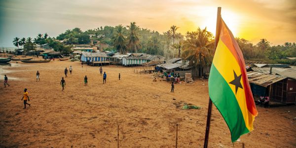 Ghana national flag with a coastal community in the background