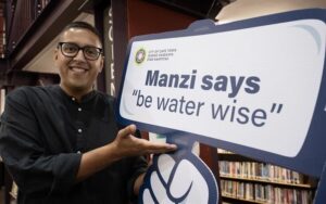 City of Cape Town representative holds a Manzi 'be water wise' sign at a school library