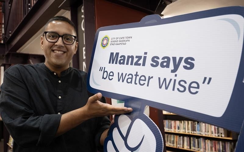 City of Cape Town representative holds a Manzi 'be water wise' sign at a school library
