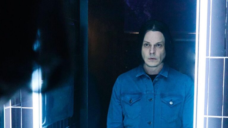 Jack White in ’n spieël weerkaats, geklee in ’n denimbaadjie, voor sy Suid-Afrikaanse konserte in 2026