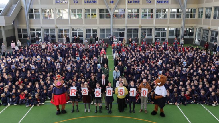 Leerders en personeel van Laerskool Eversdal hou plakkate met die bedrag R358 500 op tydens die skool se 50ste bestaansjaar-viering.