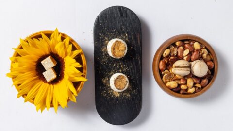 Petit fours van Salsify at the Roundhouse in Kaapstad, bedien op ’n sonneblom, ’n swart houtbord en in ’n houtbak met grondboontjies